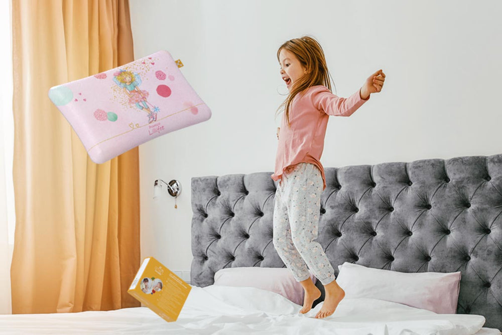 Fröhliches Mädchen springt auf dem Bett mit ihrem smart KIDS COMFORT PILLOW und einem Kissenbezug mit Prinzessin Lillifee